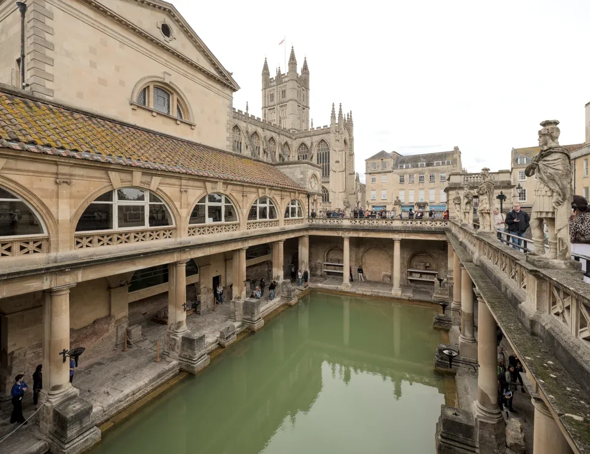 The Great Bath at the Roman Baths with Bath Abbey behind, an option on Stonehenge tours from London, Somerset